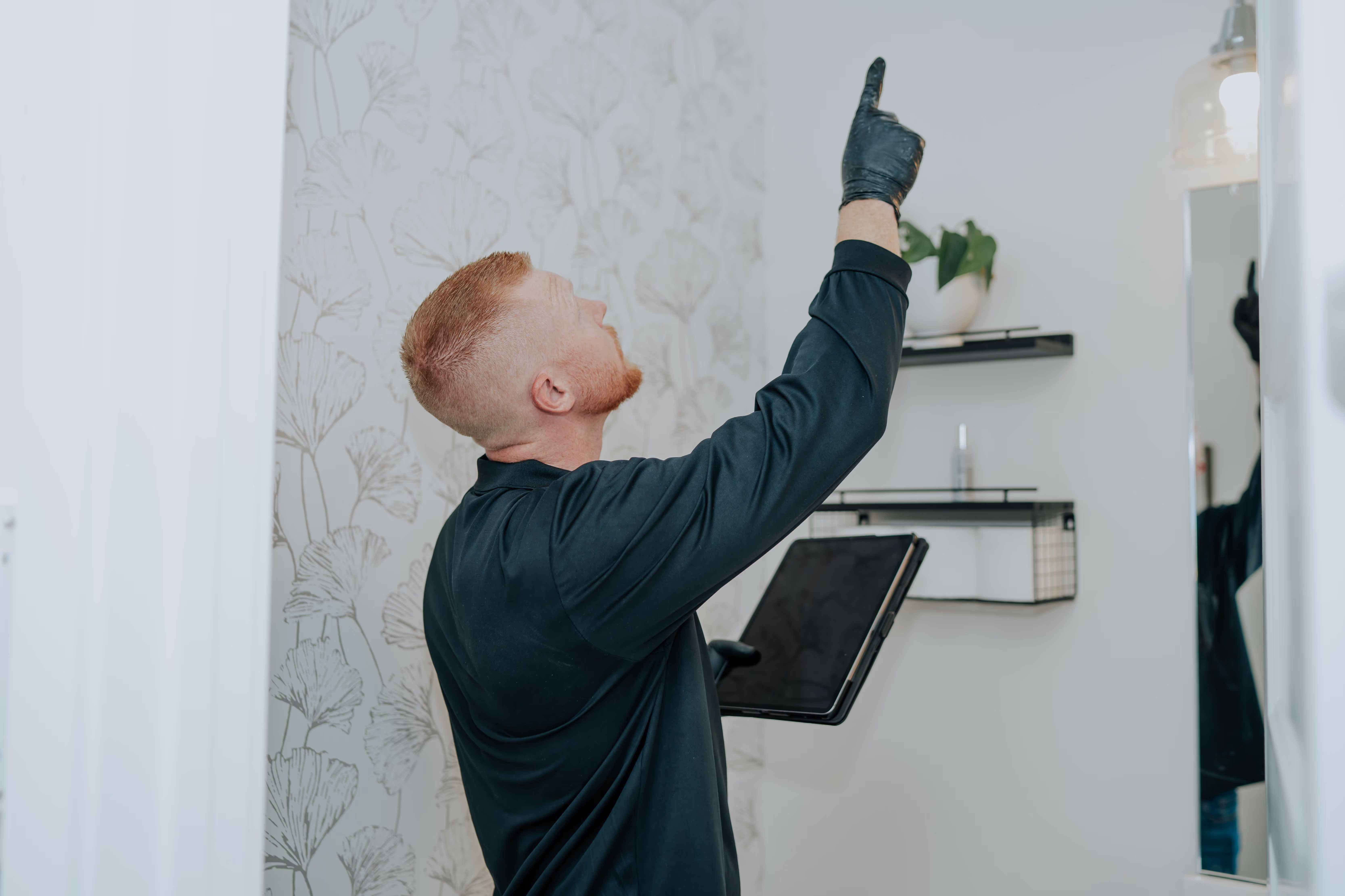 Inspector checking a wall and ceiling with a tablet in hand